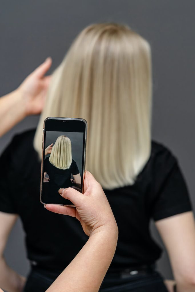 hairstylist taking photo of client for social media